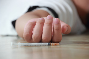 Overdose drug addict lay down on floor with a syringe near his hand